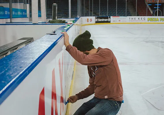 Installer applying graphics to arena boards