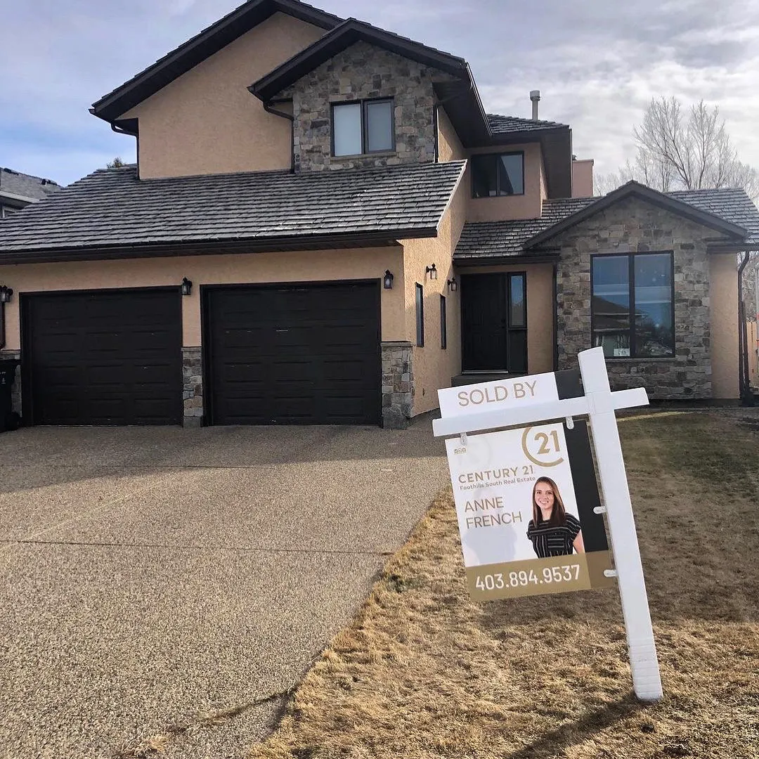 Real estate yard sign on a post in front of a house